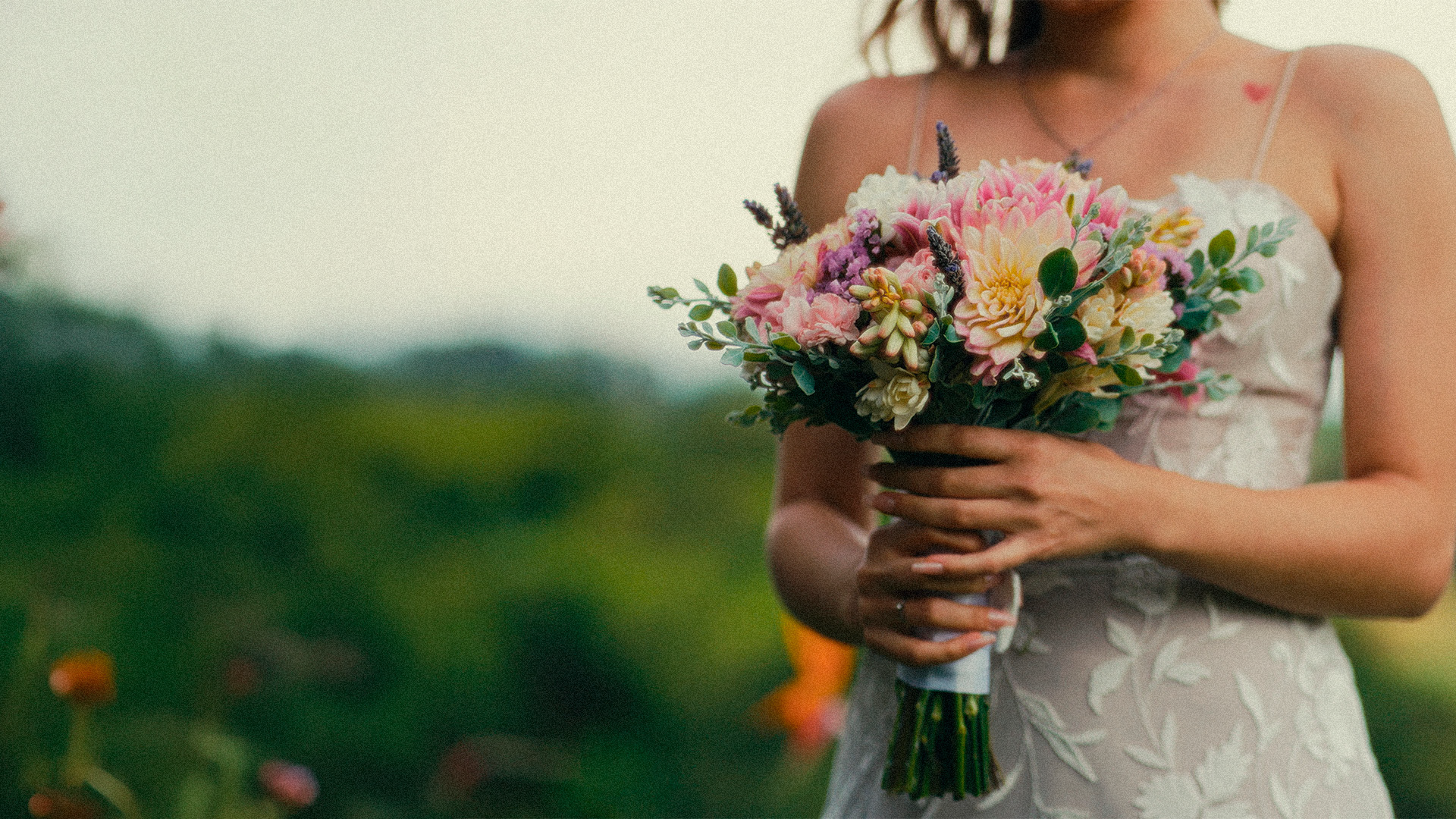 Noiva com um buquê de flores em uma paisagem verde